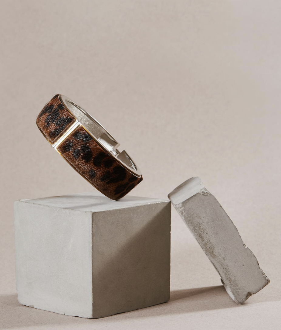 Leopard-print bracelet balanced on a concrete block
